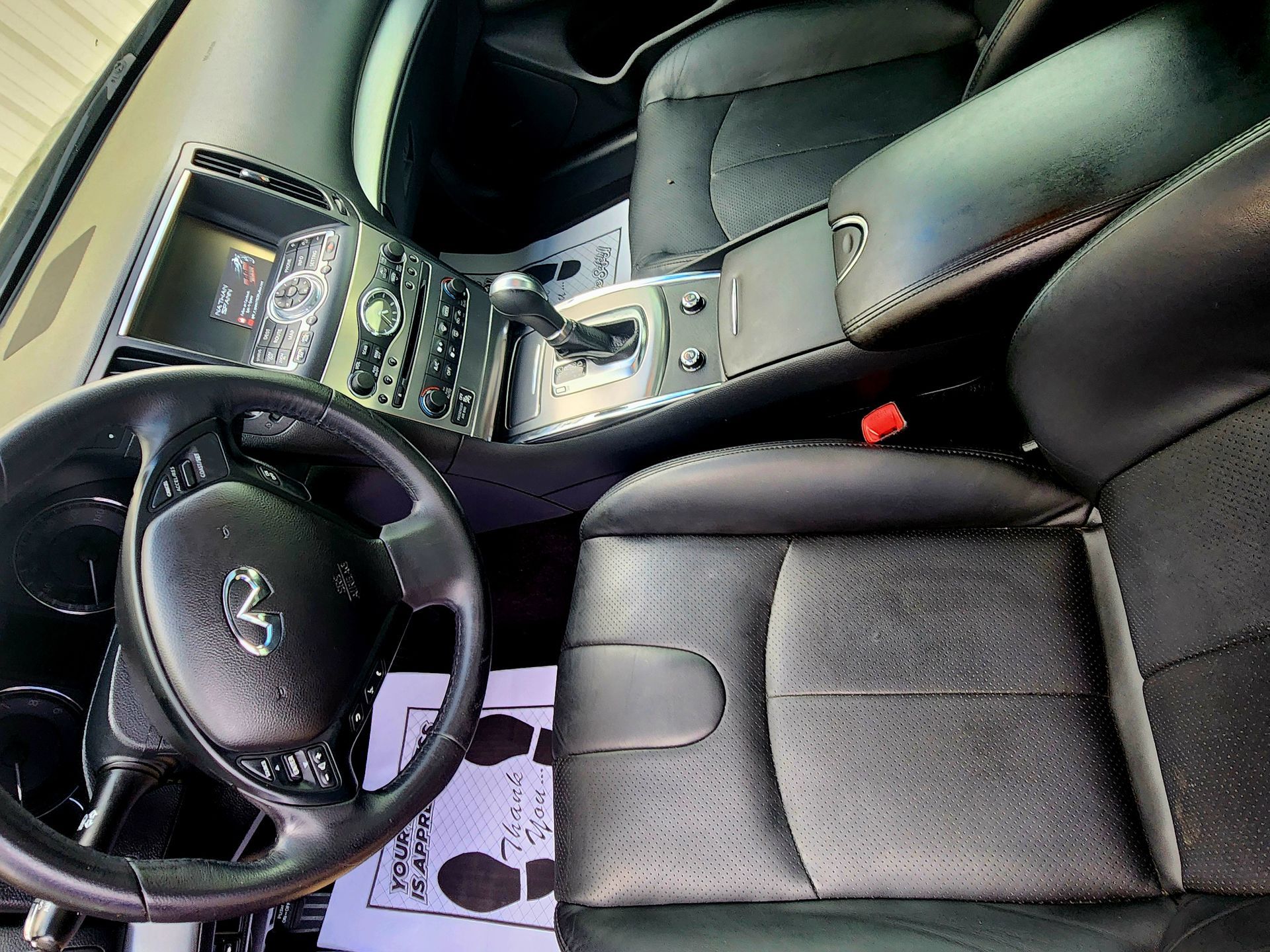 Interior of a black Infiniti car: steering wheel, dashboard, seats, and center console visible.