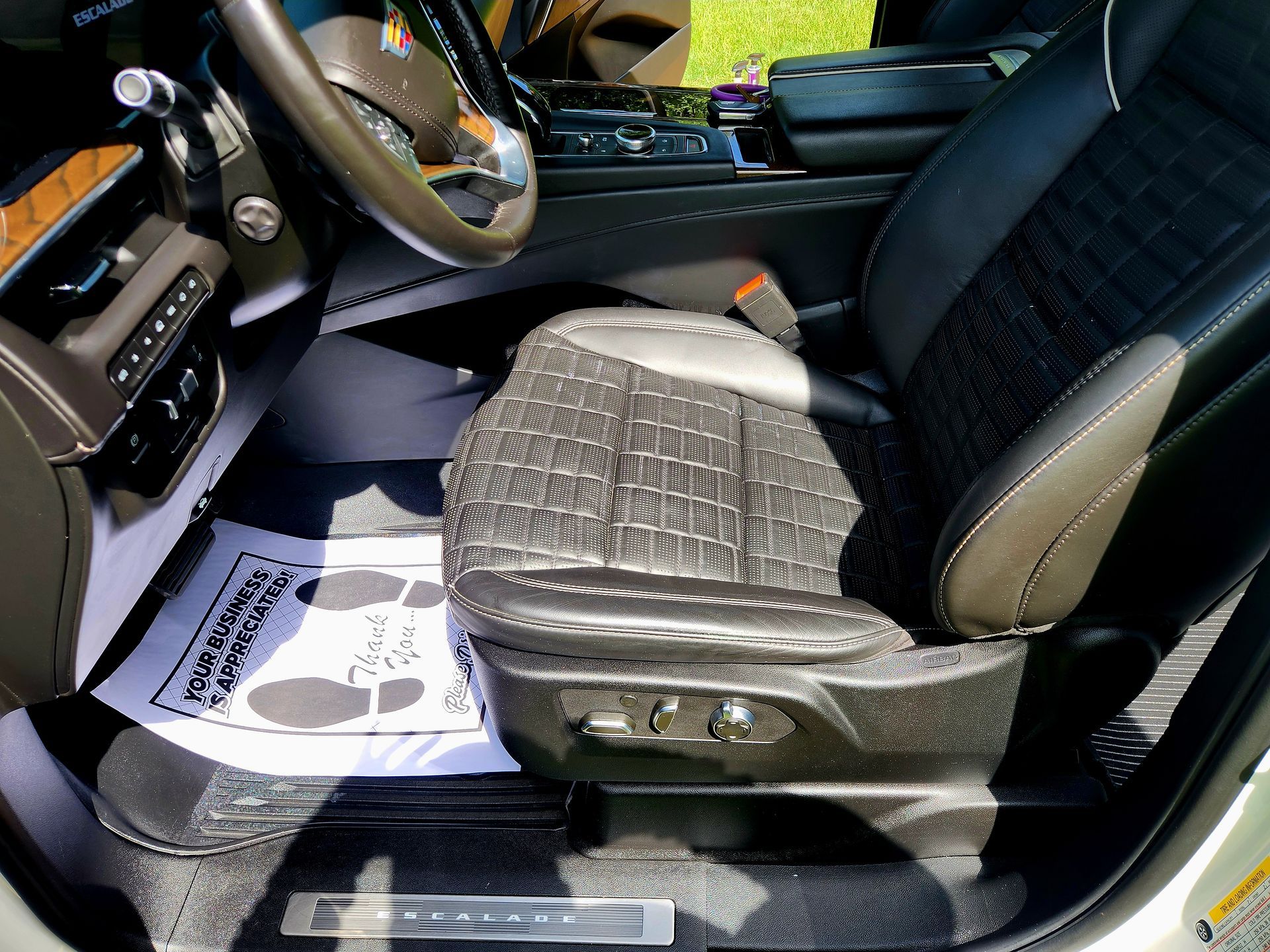 Black leather car seat in vehicle interior with white floor mat.