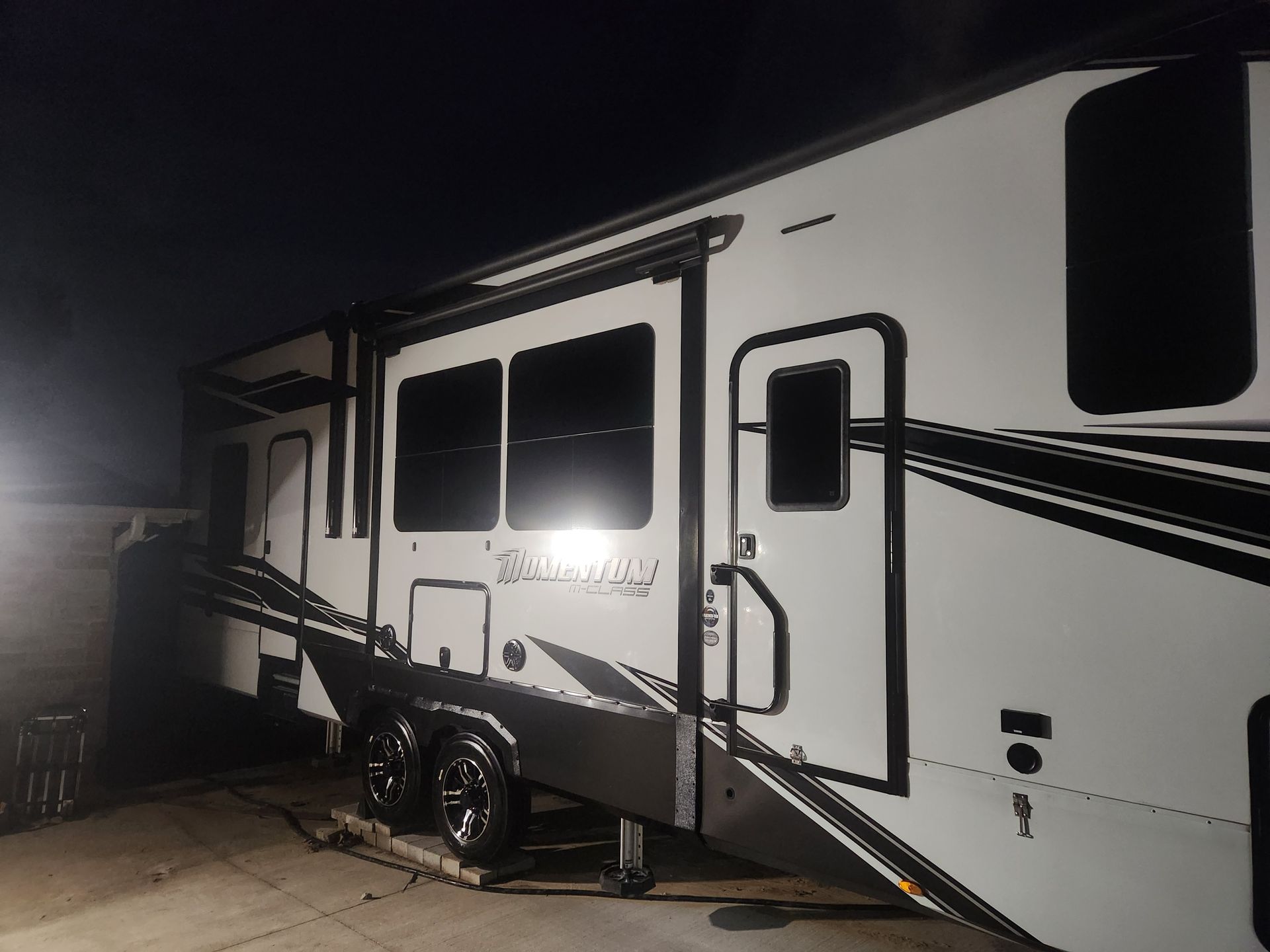 A large, white and black recreational vehicle (RV) parked outdoors at night.