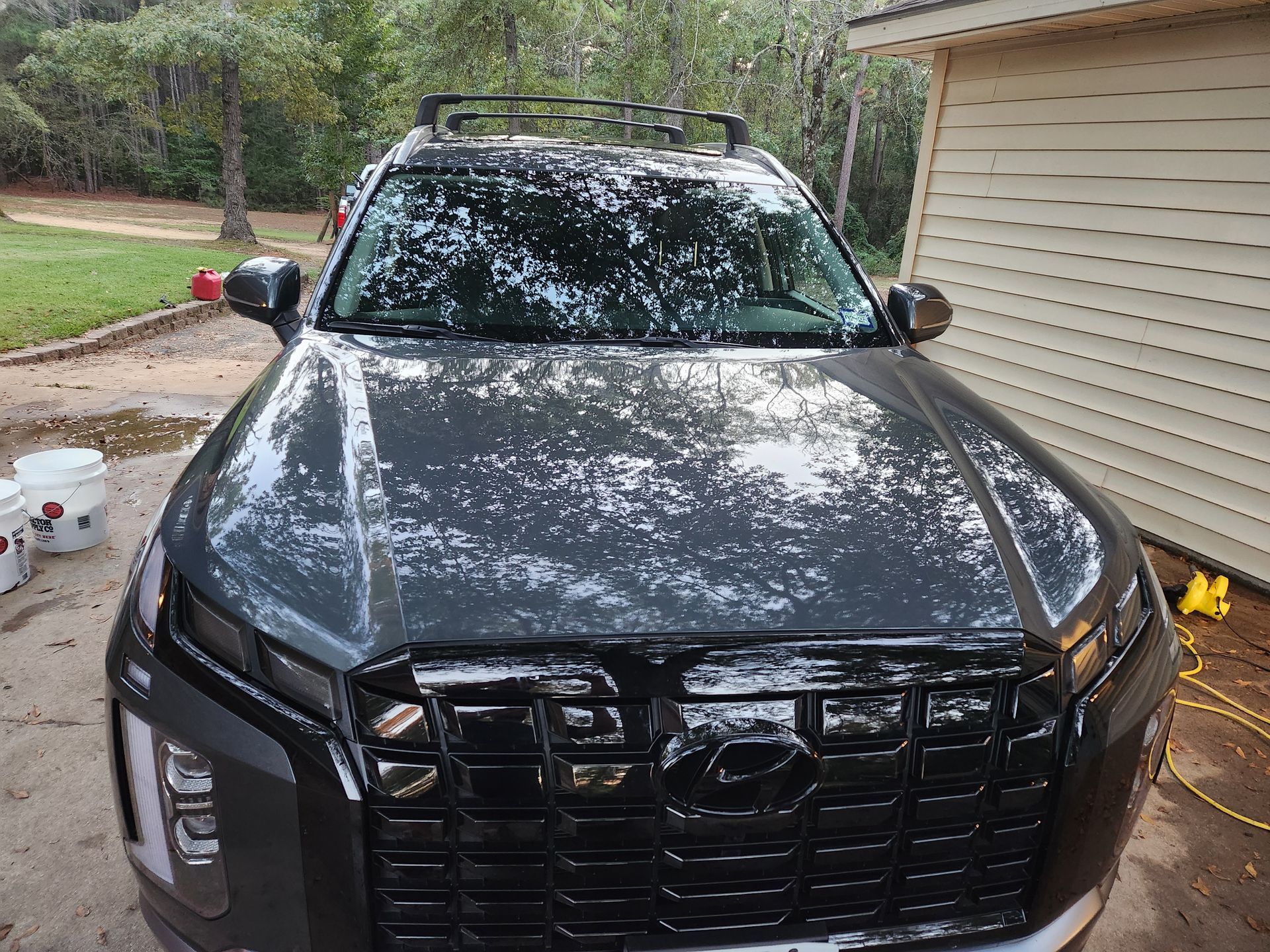 Gray SUV covered in soap suds being washed in front of a house.