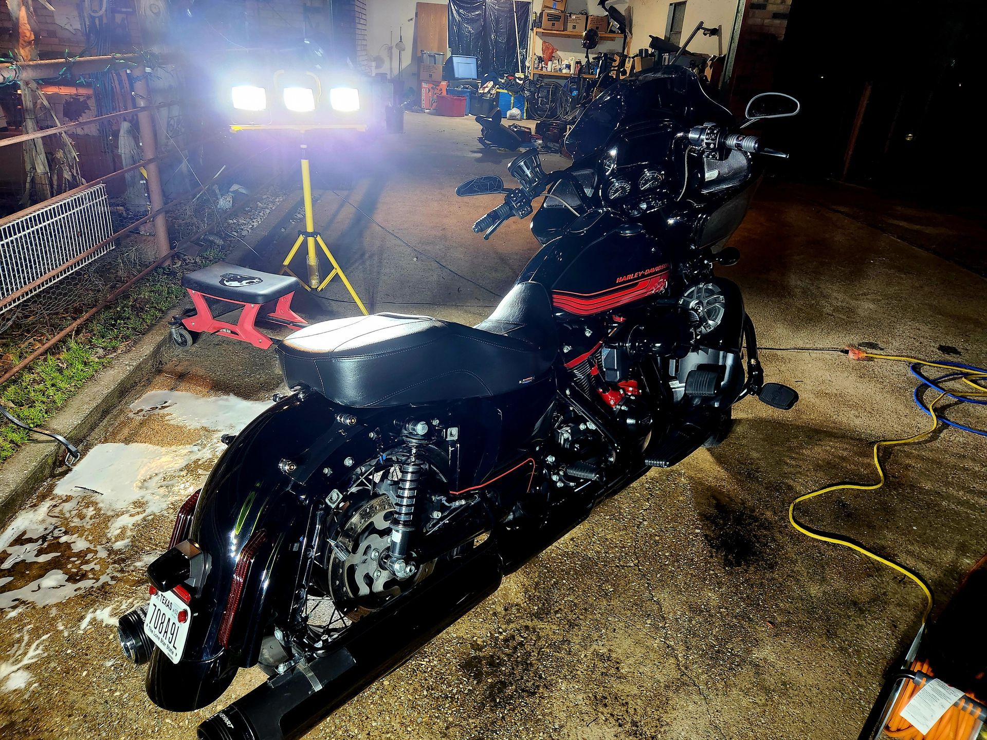 Black motorcycle being washed at night, illuminated by a work light.