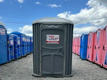 A row of portable toilets are lined up in a gravel lot.