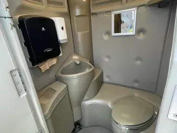 A bathroom with a toilet , sink and mirror.