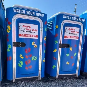 Two blue portable toilets that say watch your head