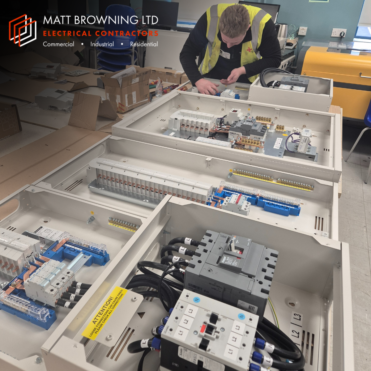 A commercial electrician from Matt Browning Electrical assembling a Hager 250A panel board and 125A three phase distribution boards with energy metering and surge protection for a school building electrical upgrade in Berkshire.