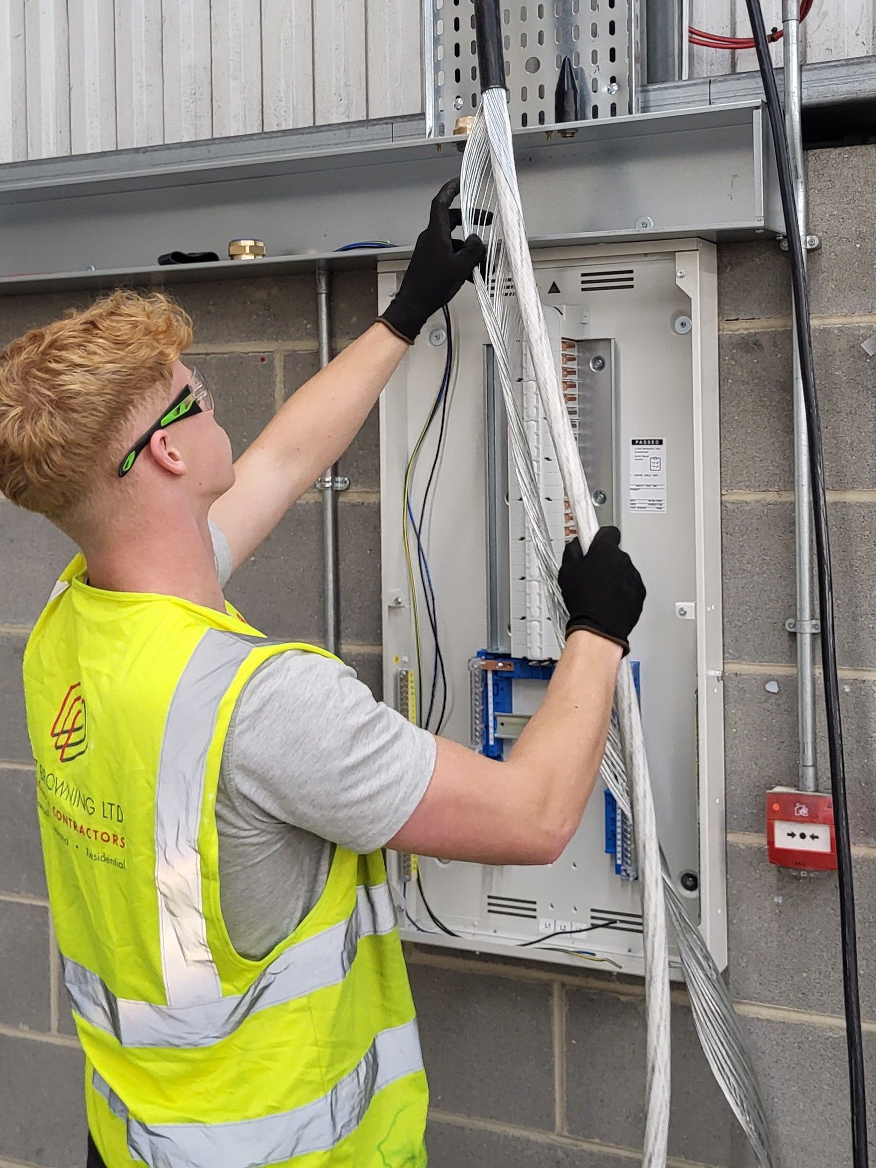 An electrical apprentice from Matt Browning Electrical is stripping the outer sheath and armouring from an SWA cable submain ready to gland and terminate it into a 3-phase distribution board on a commercial industrial electrical fit-out project near Slough and Reading. The distribution board will supply electrical power to fork lift chargers, 3-phase machines, sockets, and lighting.