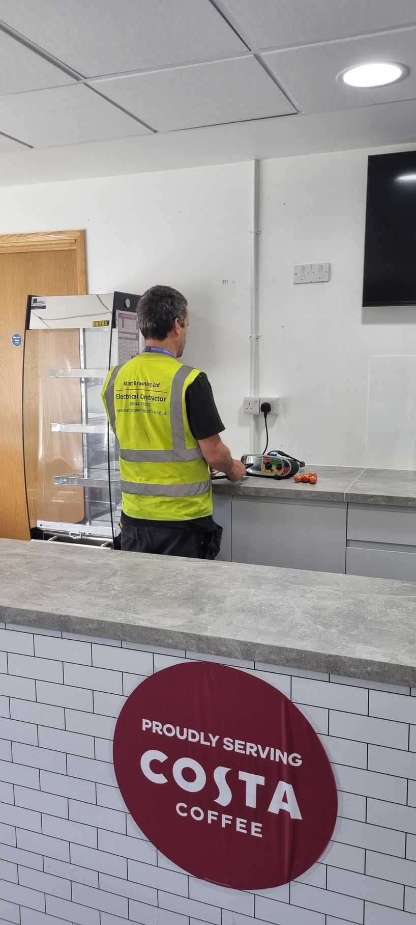 Electrician working in a school, carrying out electrical safety testing of electrical installation