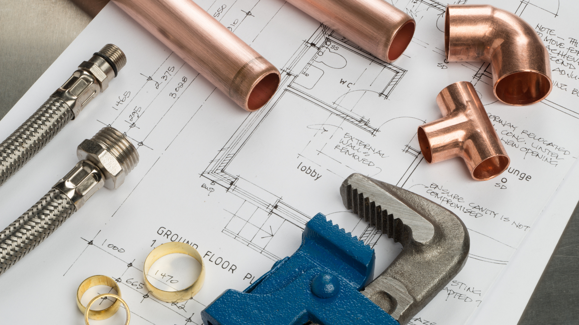 Copper pipes and a wrench on top of a blueprint