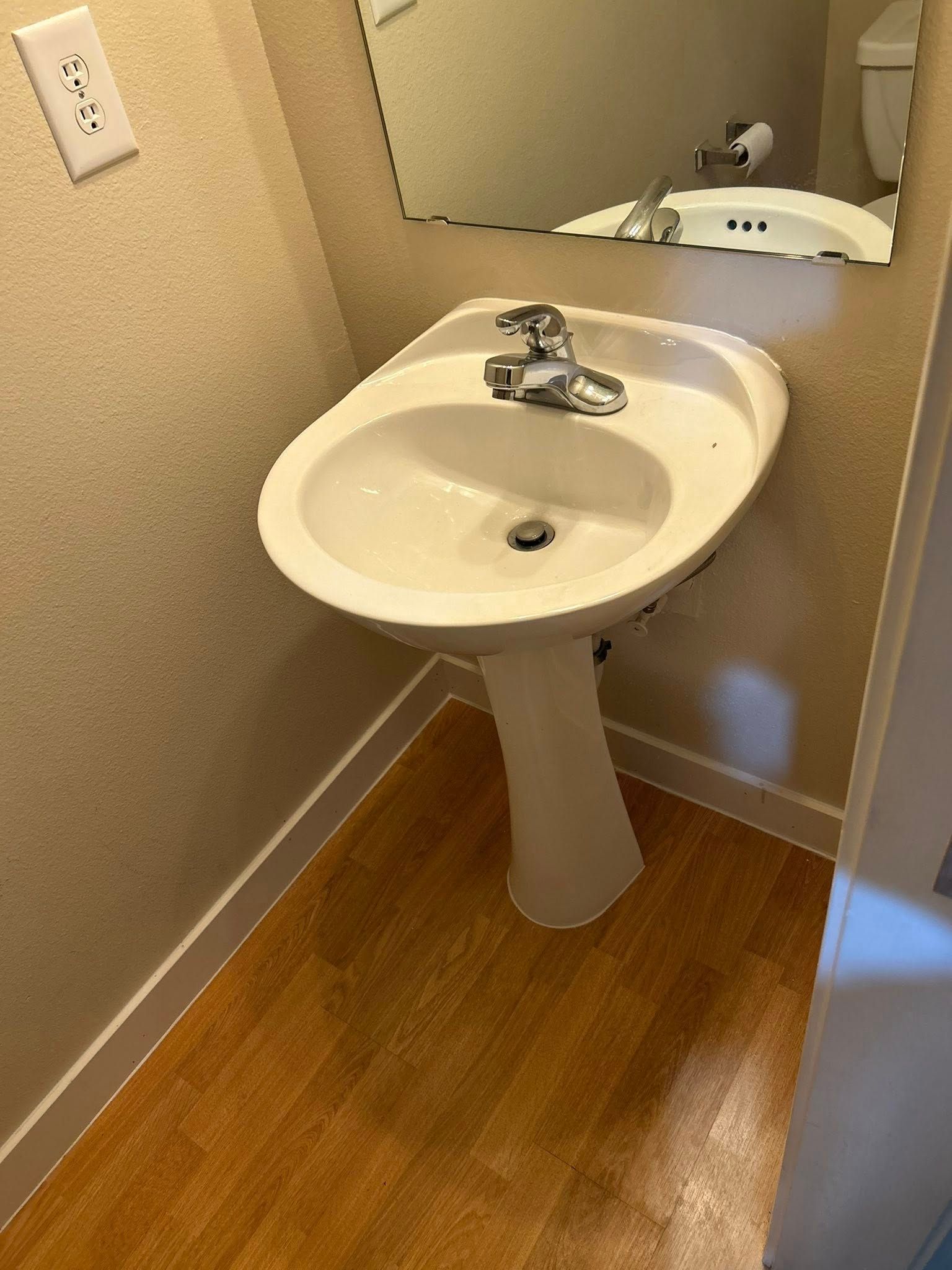 Small bathroom with a pedestal sink and a mirror.
