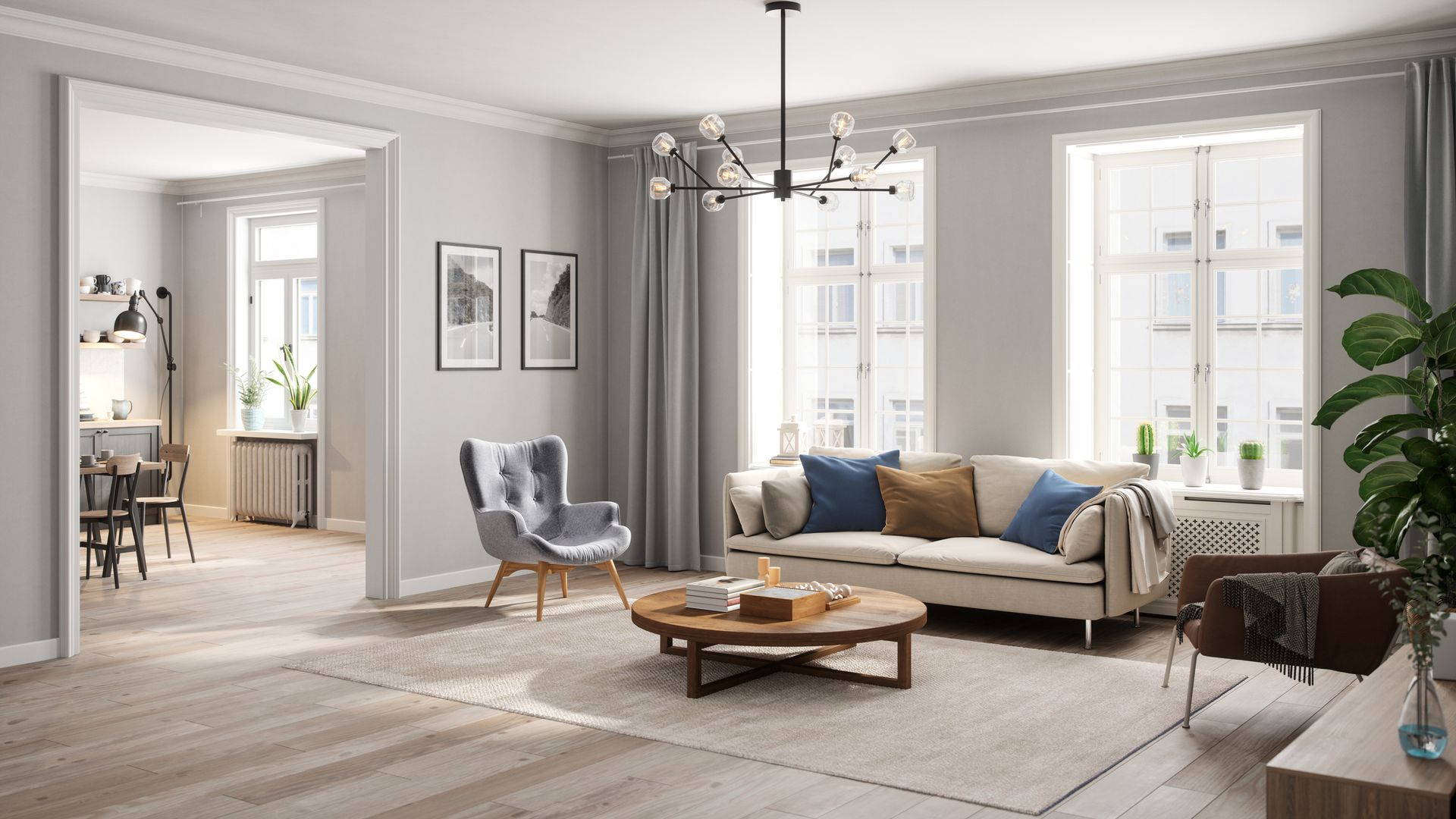 Living room with sofa, armchairs, and round coffee table on a rug. Light gray walls, large windows, and a modern chandelier.