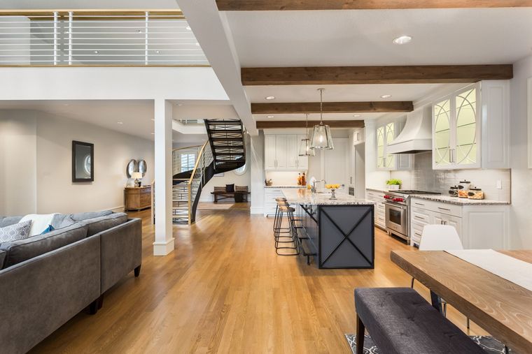 Open-concept kitchen and living area with hardwood floors, a spiral staircase, and a gray sofa.