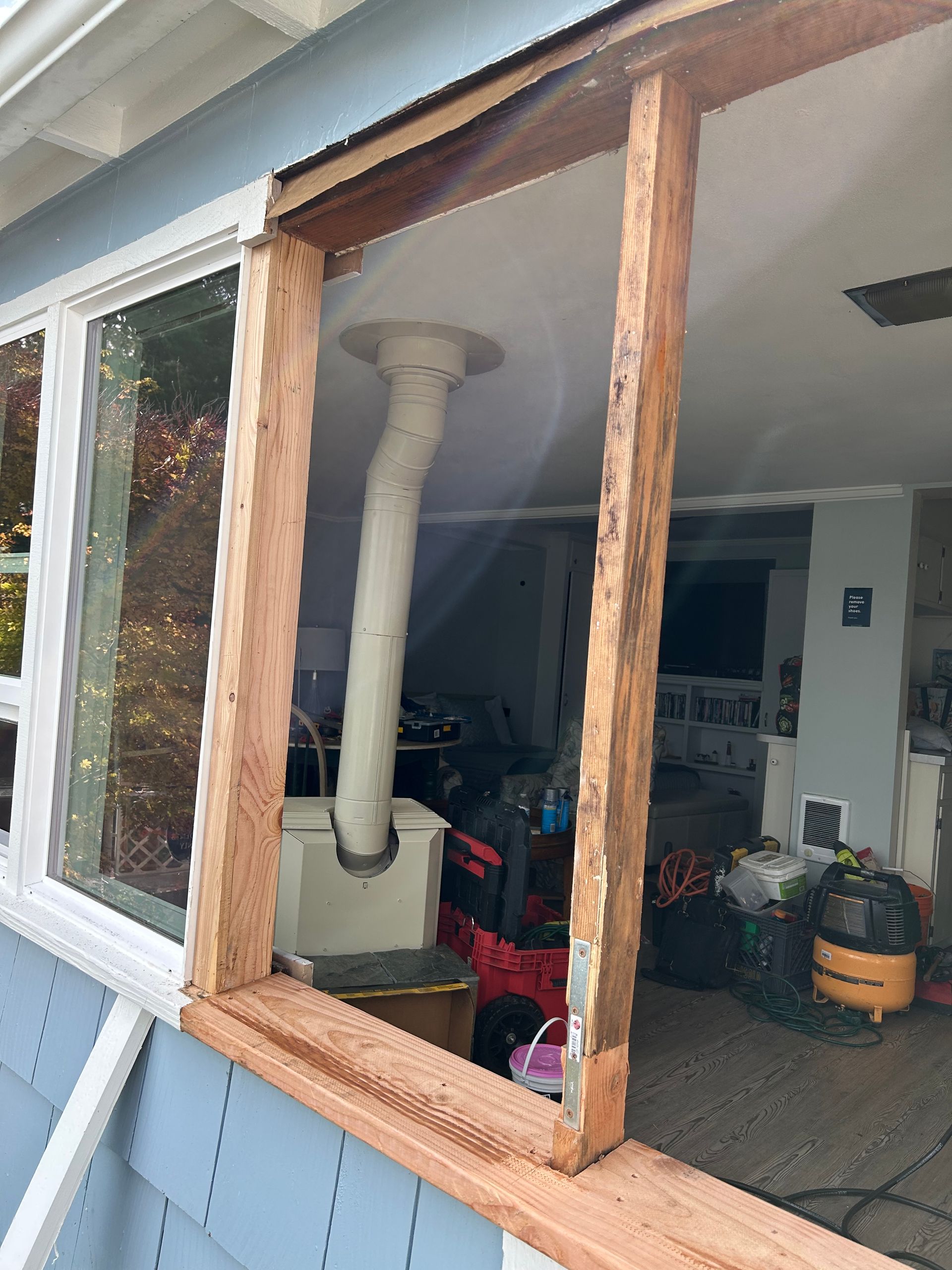 Window frame partially removed, revealing interior with vent, tools, and vacuum.
