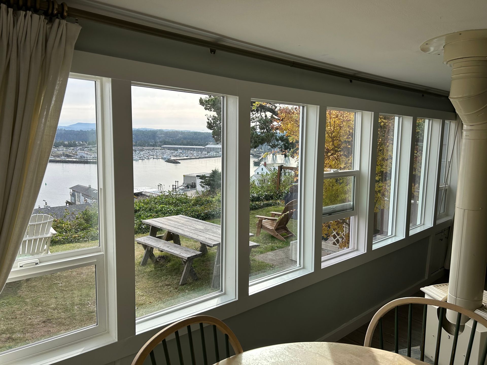 View from a room with large windows overlooking a harbor and a picnic table.