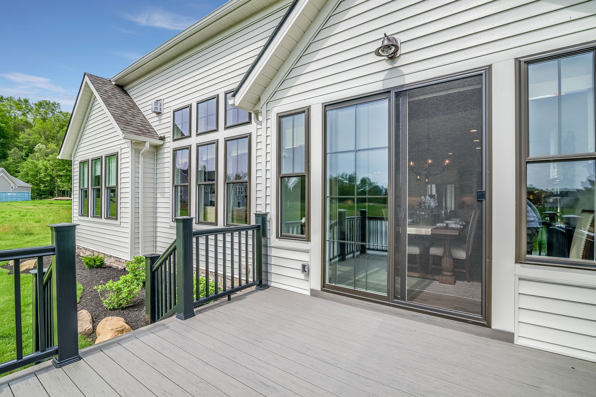 Exterior of a white house with a deck, black railings, and glass sliding door.