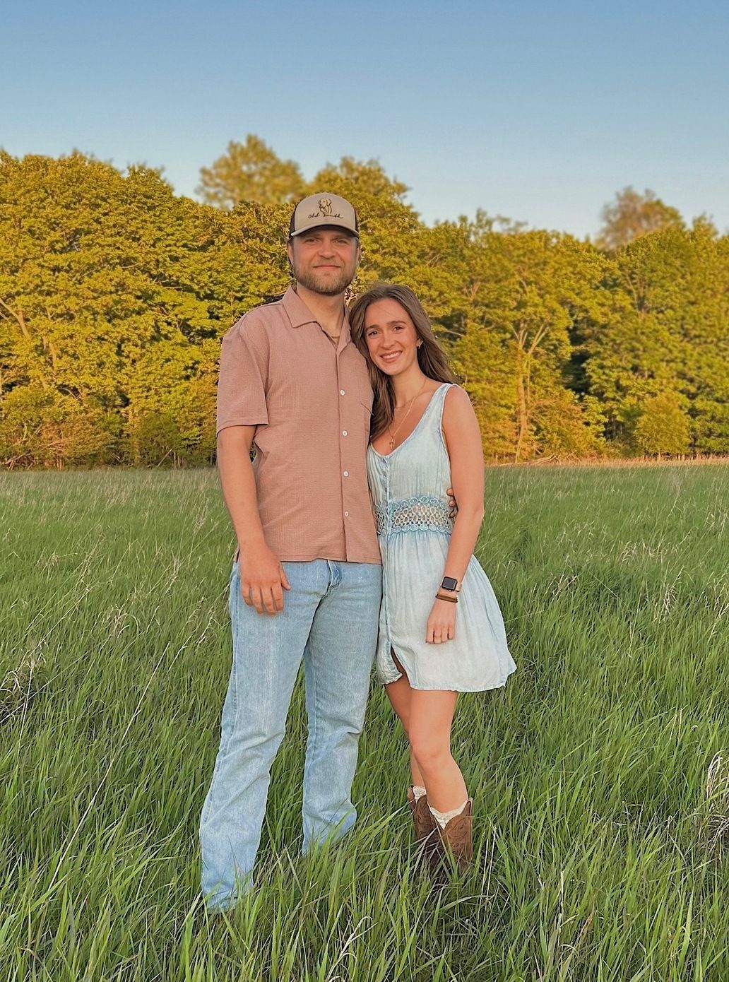A man and a woman are standing in a grassy field.