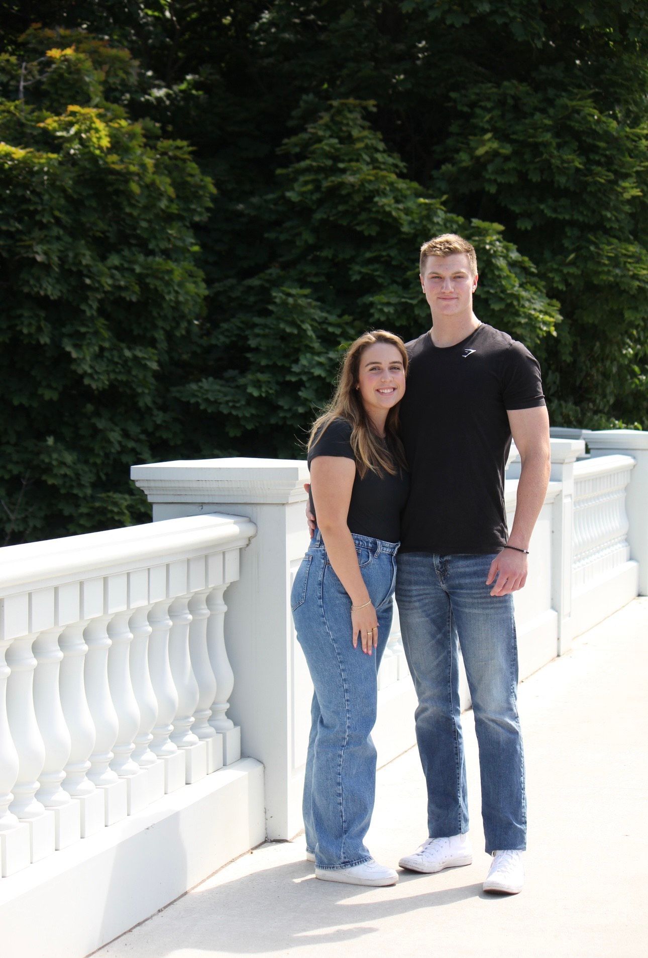 A man and a woman are standing next to each other on a bridge.