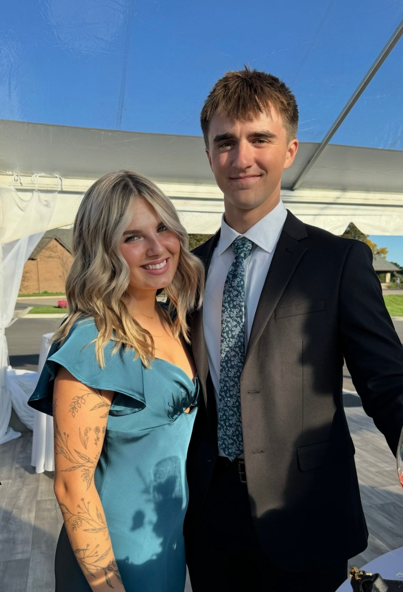 A man in a suit and tie is standing next to a woman in a blue dress.