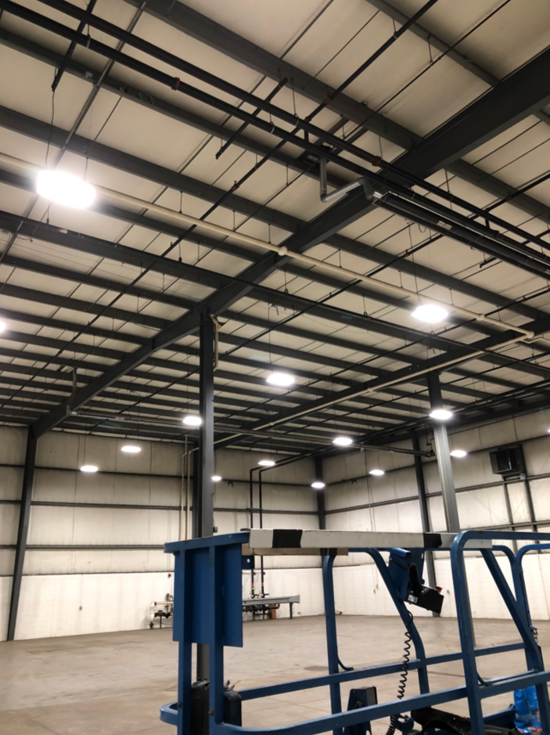 A large warehouse with a lot of pipes hanging from the ceiling