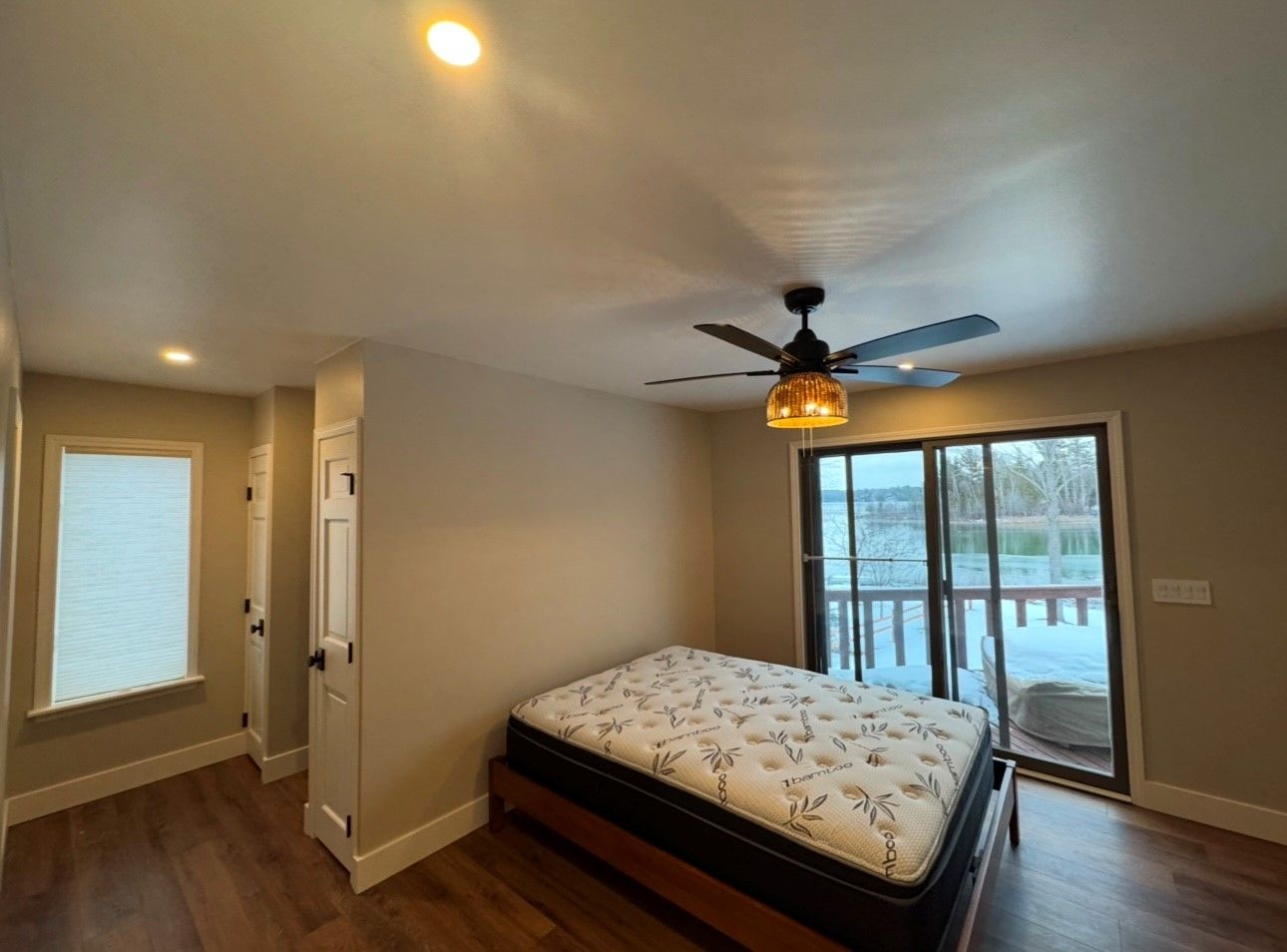 A bedroom with a bed , ceiling fan , and sliding glass doors.