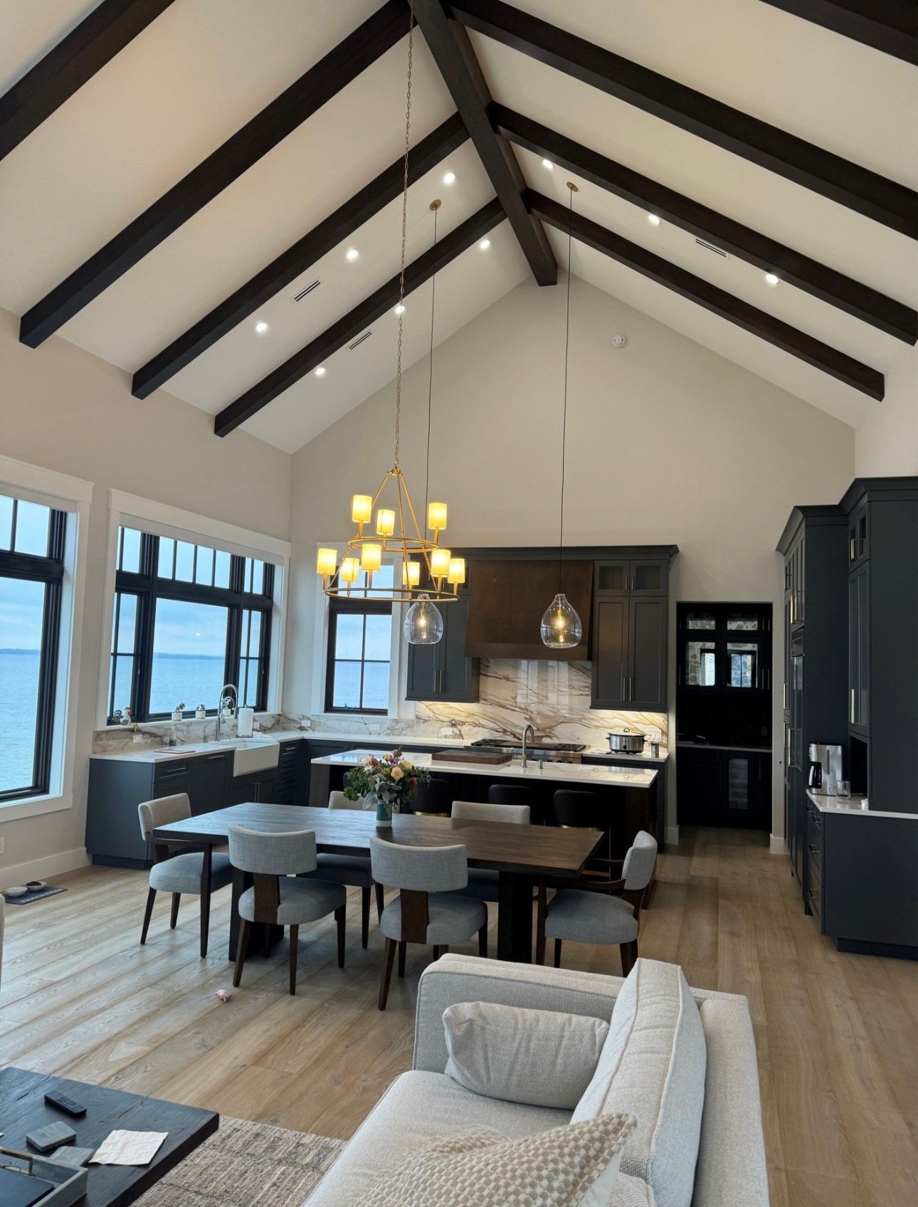 A living room with a couch , table , chairs and a vaulted ceiling.