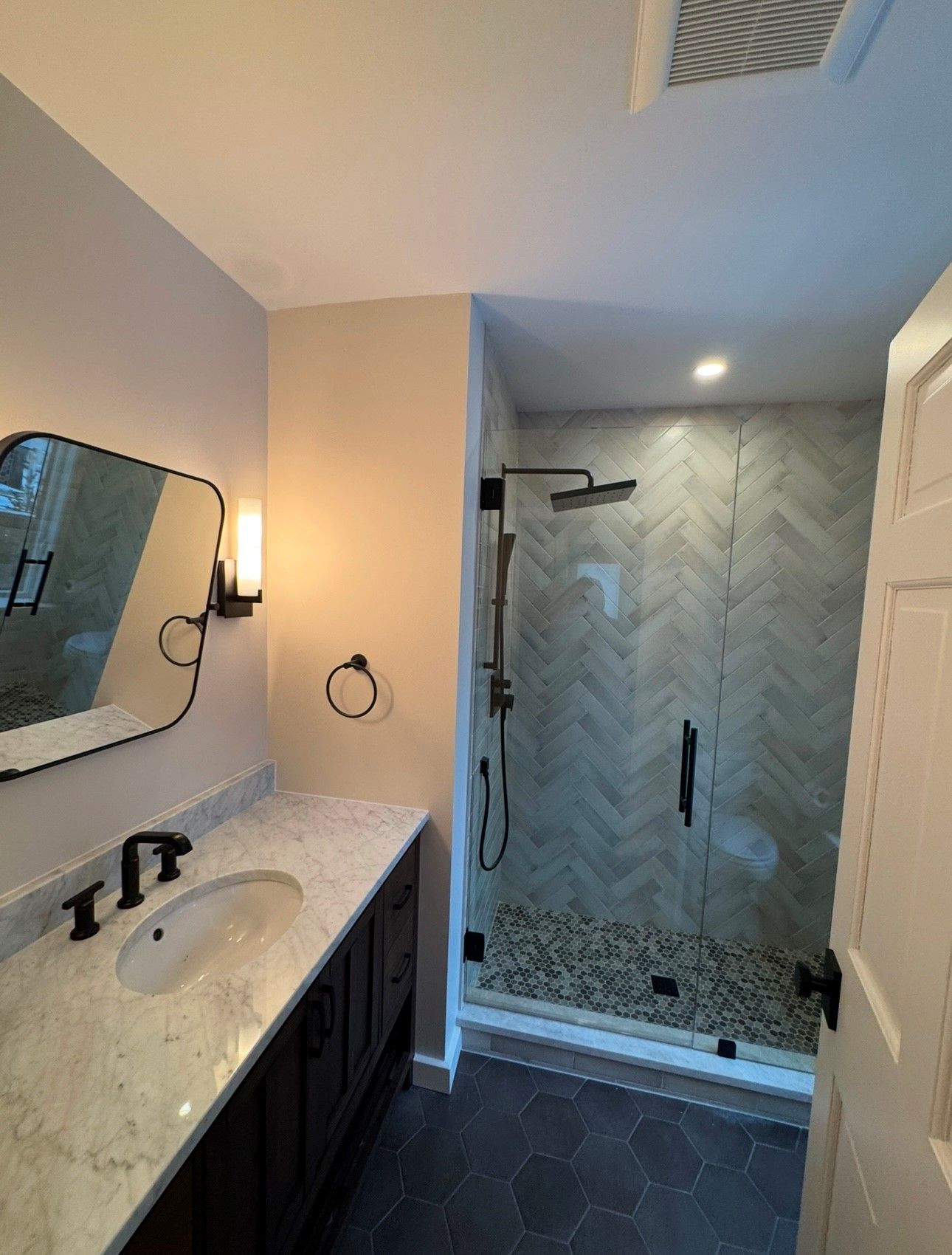 A bathroom with a sink , mirror and shower.