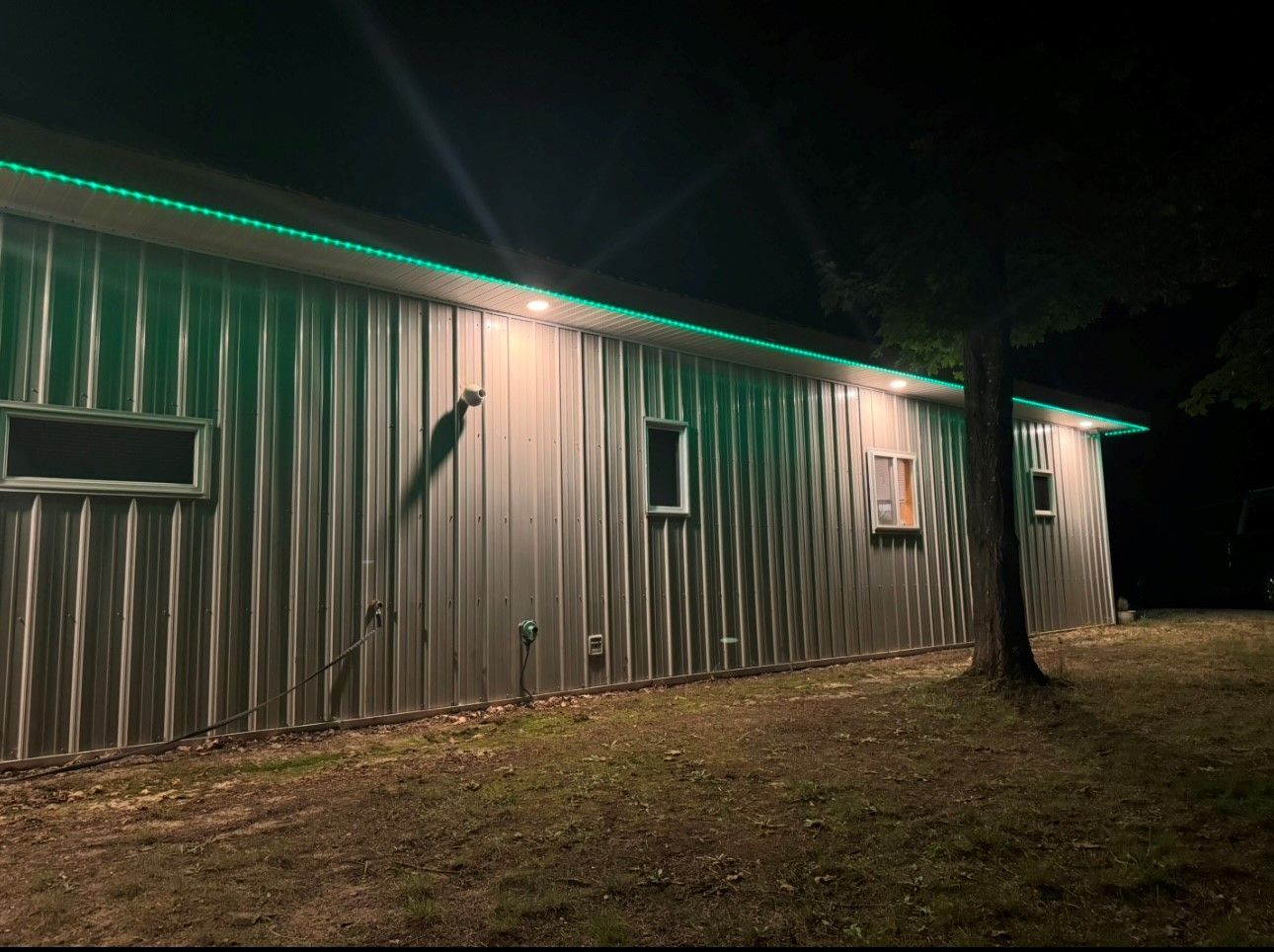 A large building with green lights on it is lit up at night.