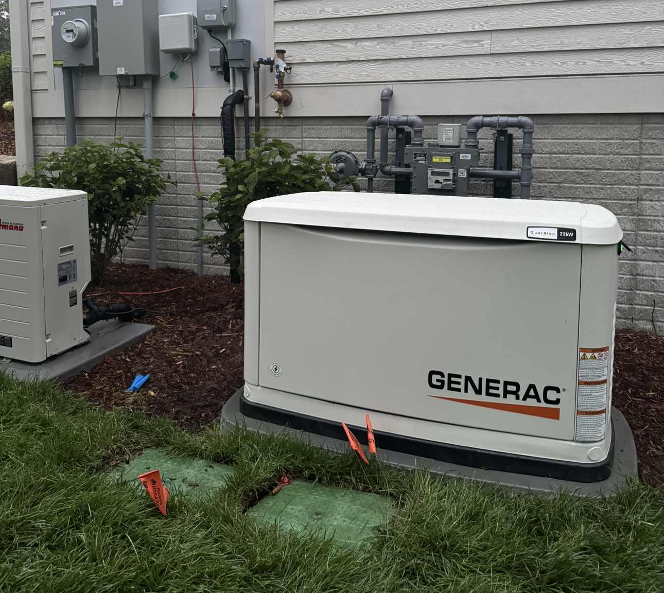 A generator is sitting in the grass in front of a house.