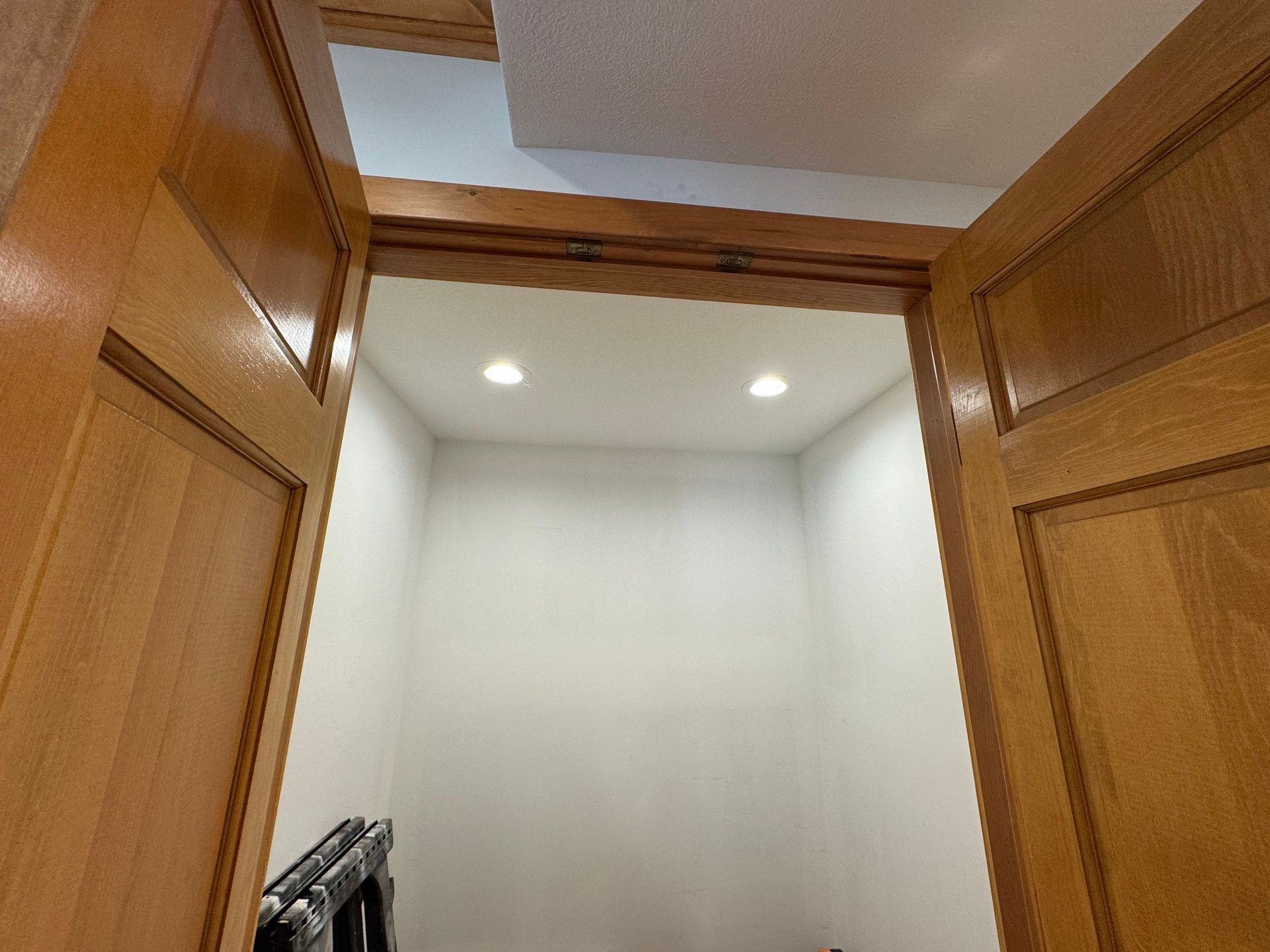 A closet with wooden doors and white walls.