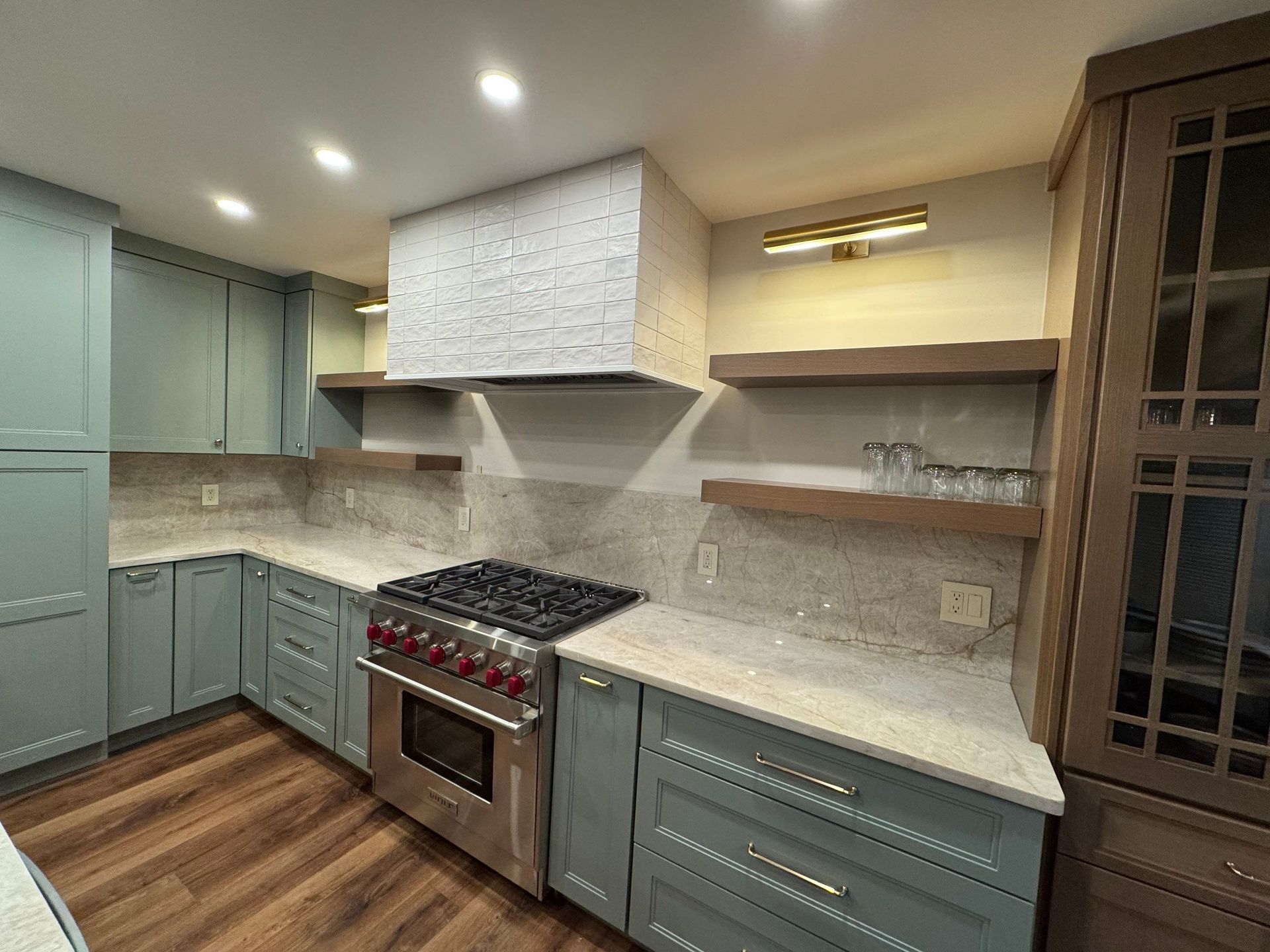 A kitchen with blue cabinets , stainless steel appliances , and a stove top oven.
