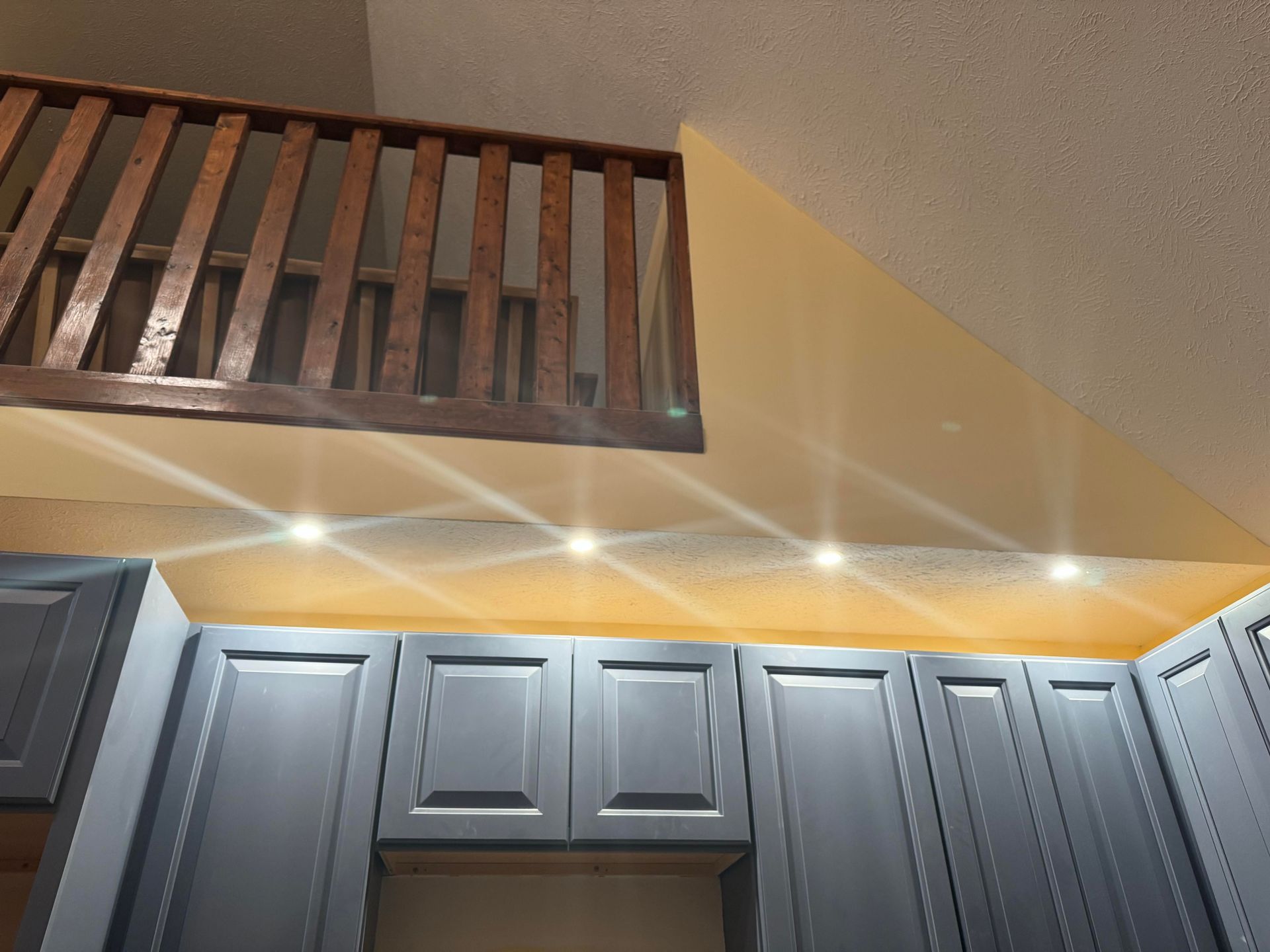 A kitchen with gray cabinets and a wooden railing