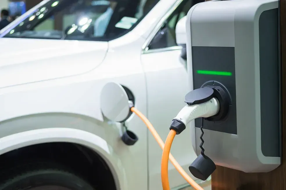 A white electric car is being charged at a charging station.