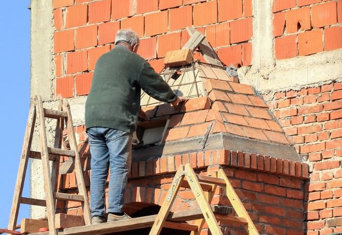 Worker on a wooden scaffold repairing a brick wall with a trowel