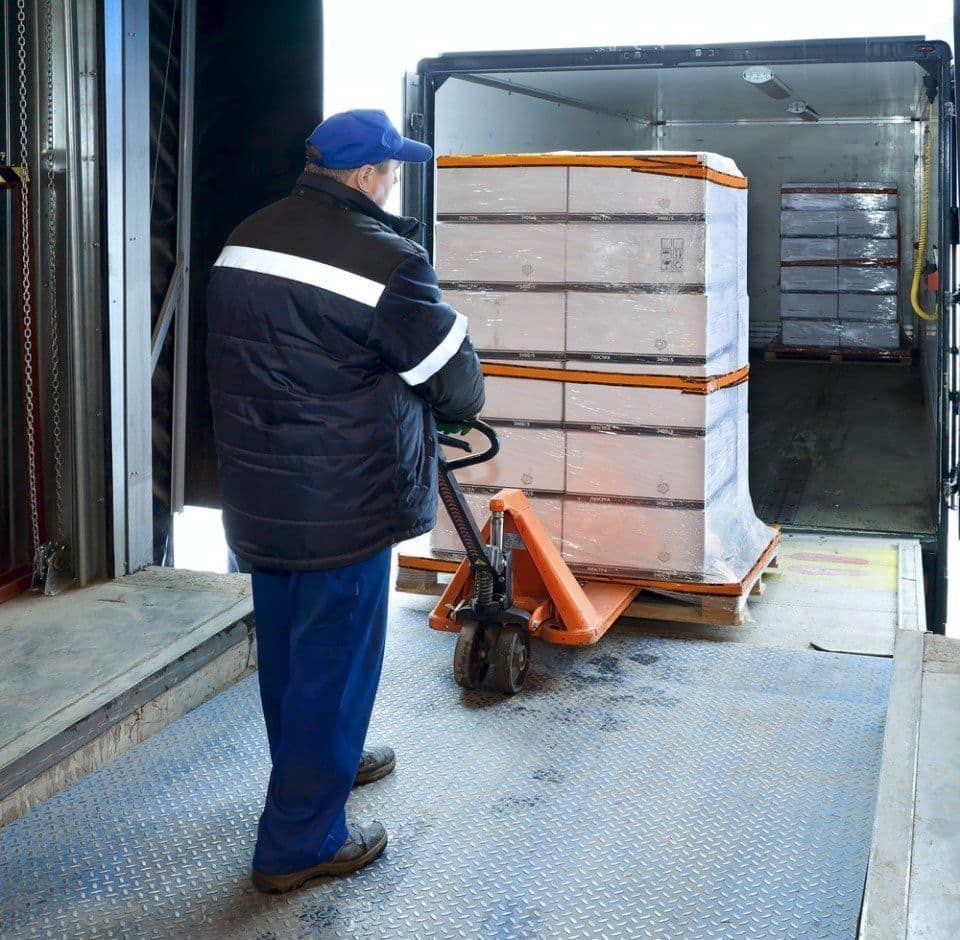 A Man Is Loading Boxes Into A Truck With A Hand Truck — LEA Distribution In Dubbo, NSW