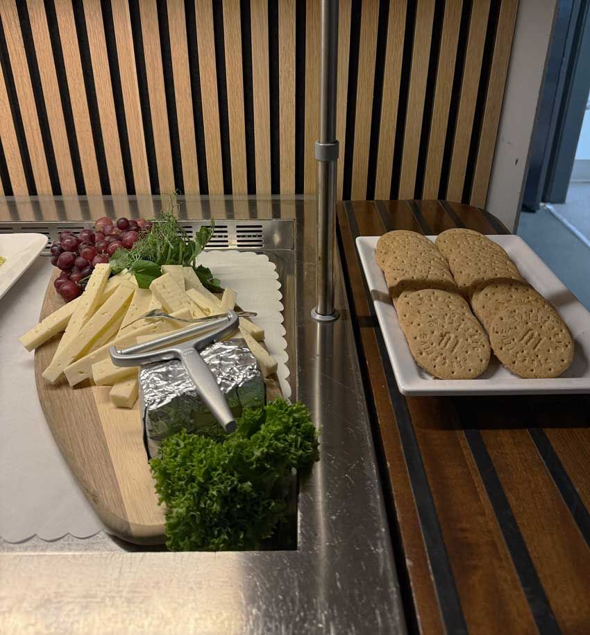 Ostefad med druer og persille ved siden af ​​skiveskåret brød på en buffetdisk
