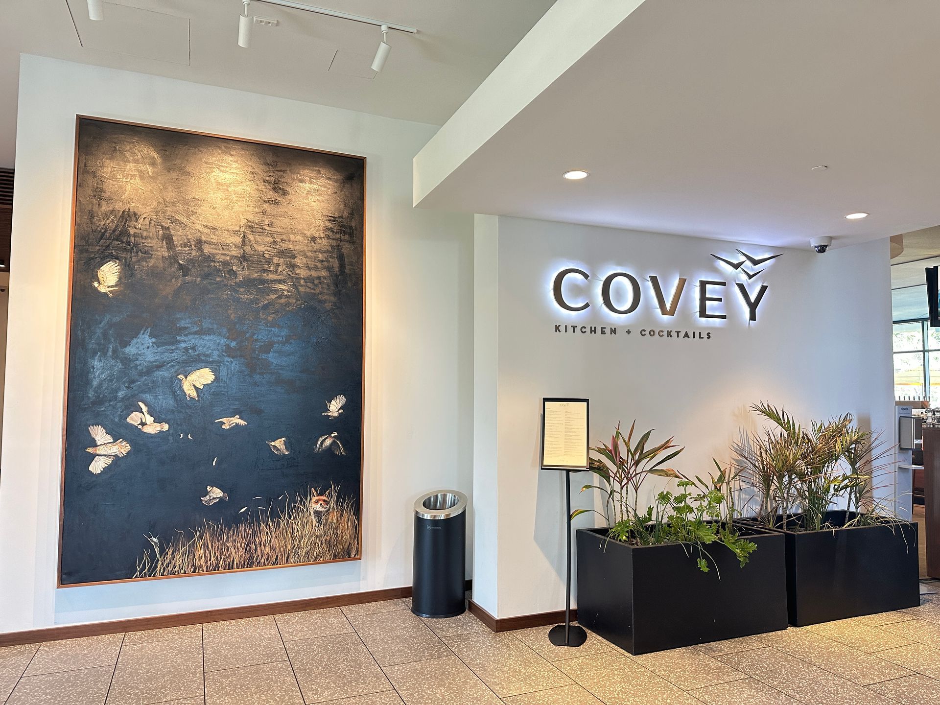 The entrance of Covey Kitchen Restaurant. A painting of a covey of quail and a fox. 