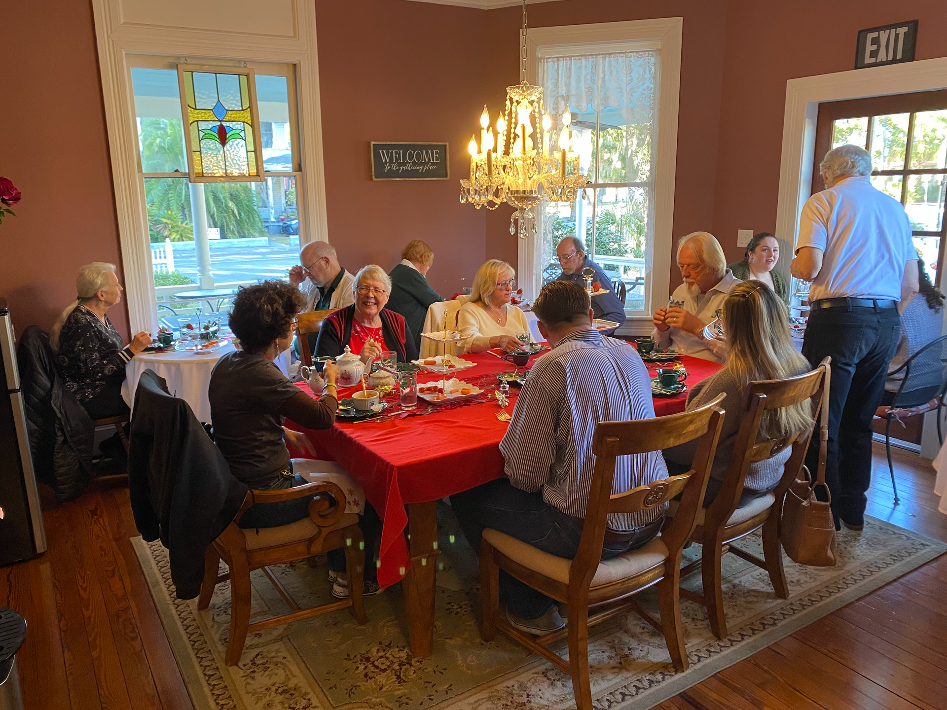 A group of happy people enjoying tea in the dining room at The Camellia Rose Inn.