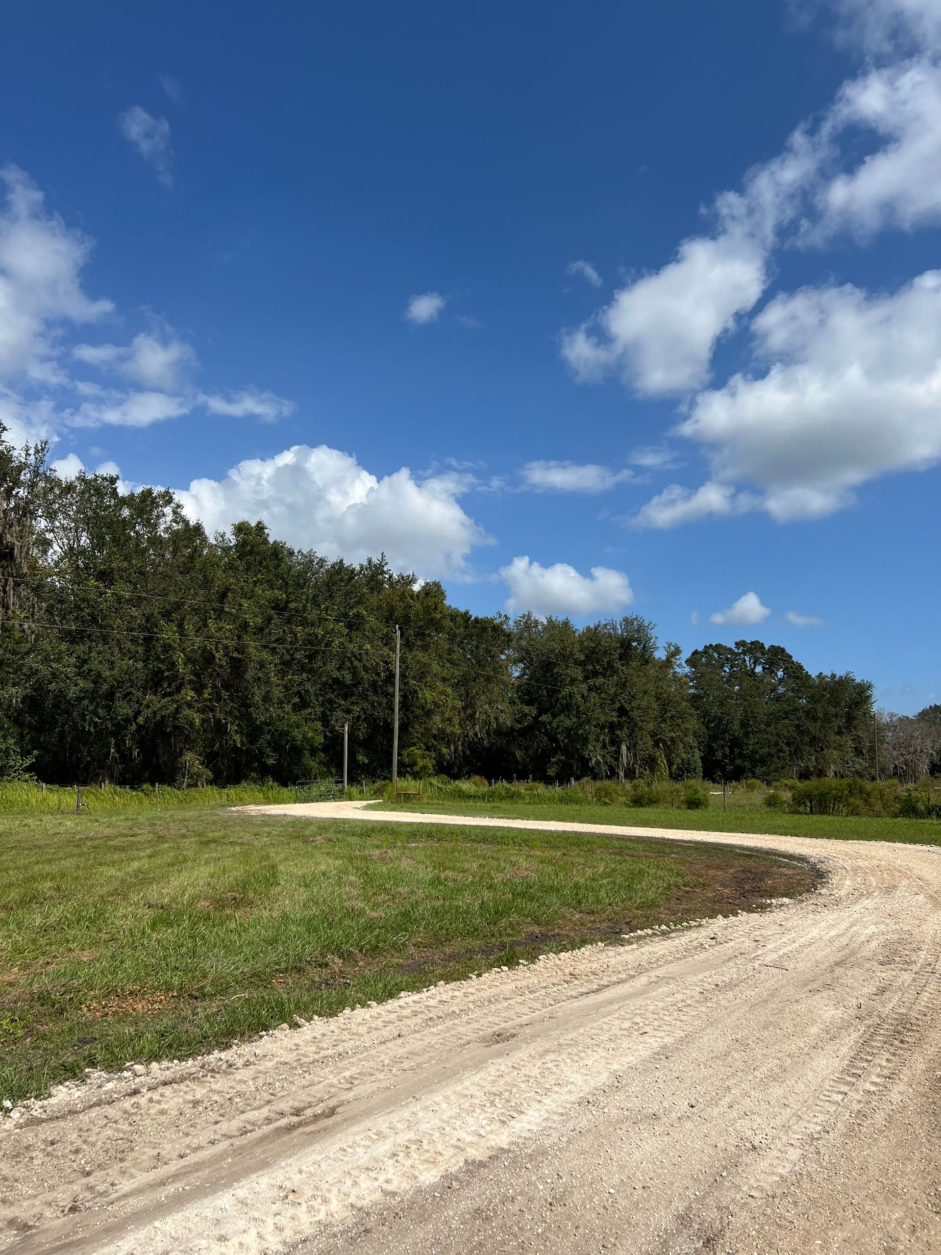 There is a dirt road going through a grassy field. - Midland Contractors - Clermont, FL