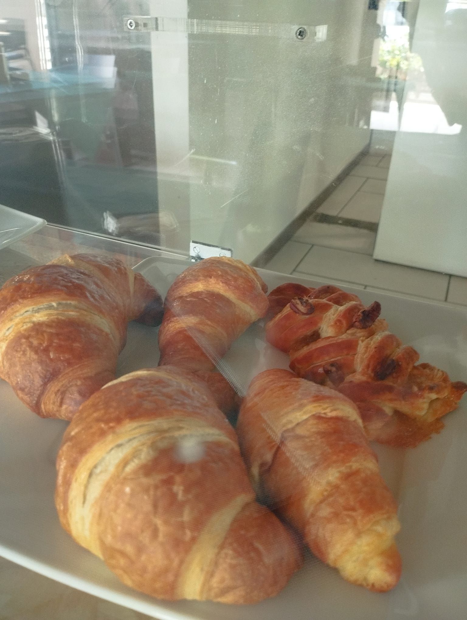 Croissant esposti in una teca di vetro; dorati, con strati sfogliati. L'ambiente sembra quello di una panetteria o di un bar.