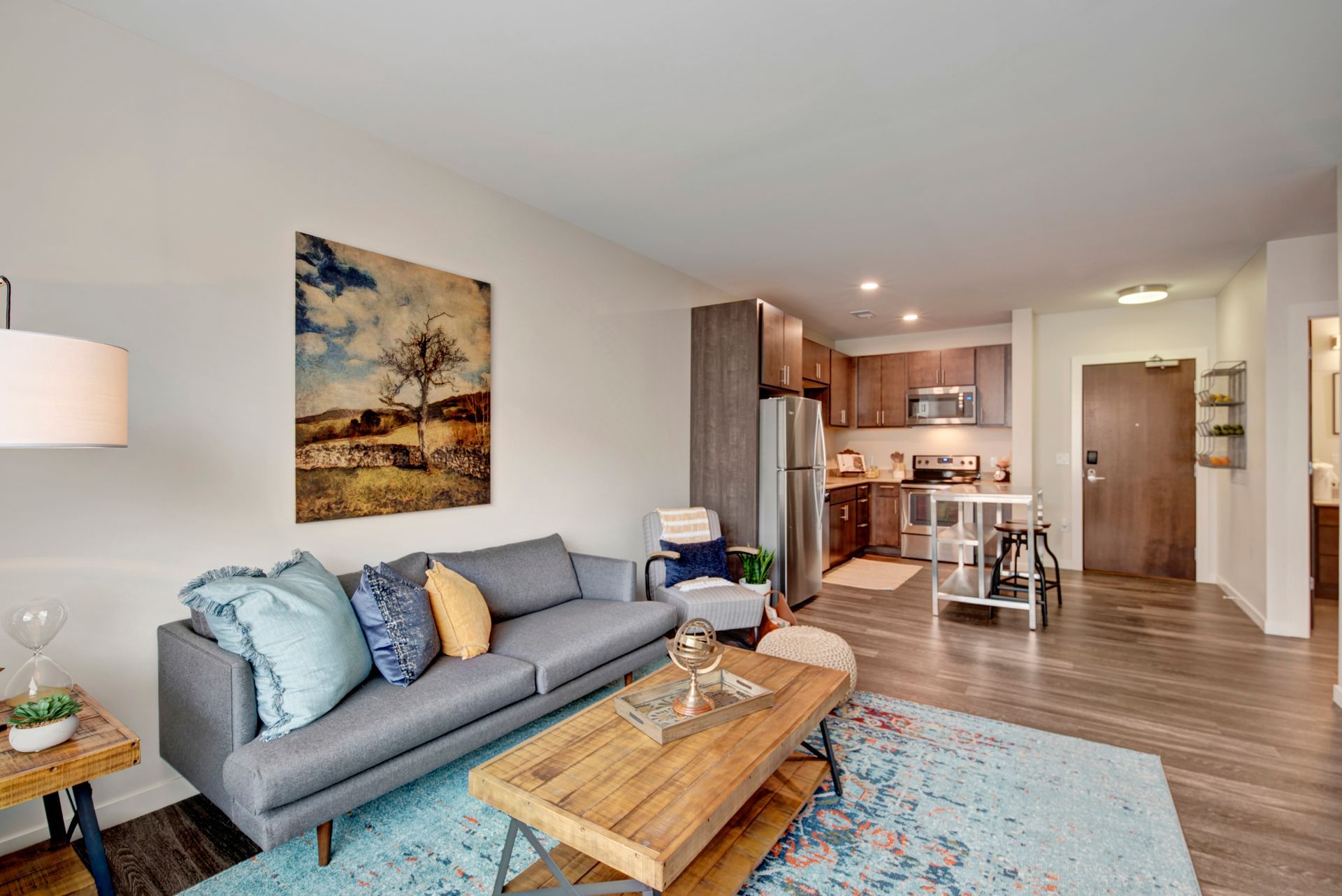 A living room with a couch , coffee table , and a painting on the wall.
