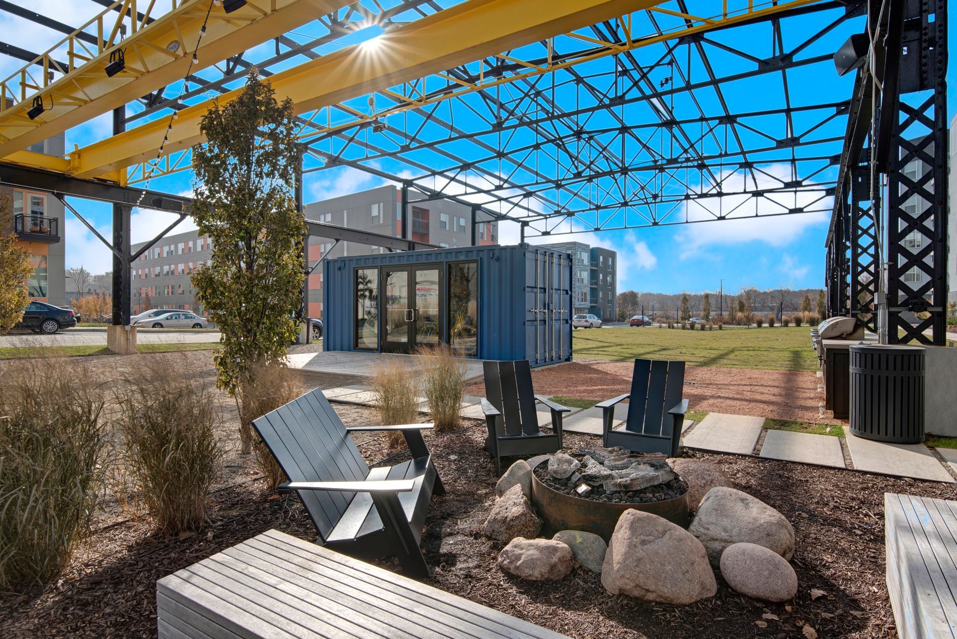 A patio area with chairs and a fire pit under a canopy.