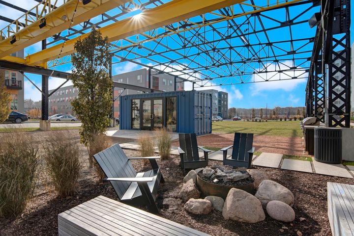 A patio area with chairs and a fire pit under a canopy.