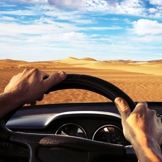 A person driving a car with their hands on the steering wheel