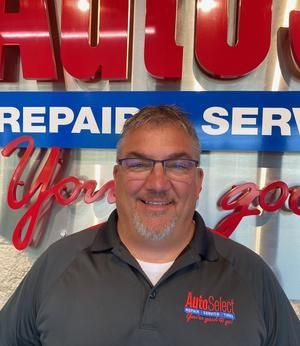 A man is smiling in front of a sign that says repair service