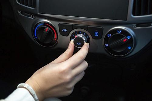 A person is adjusting the air conditioning in a car.