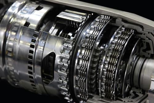 A close up of a metal gearbox on a black background.