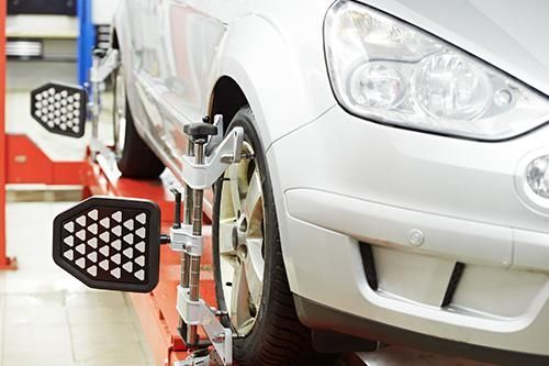 A car is being aligned on a lift in a garage.