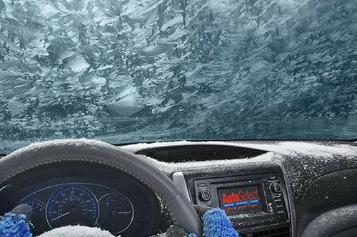 The inside of a car with snow on the dashboard and windshield.