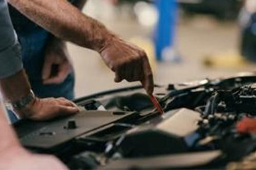 A man is working on the engine of a car in a garage.