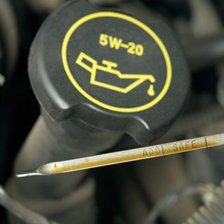 A close up of a 5w-20 oil cap and a dipstick