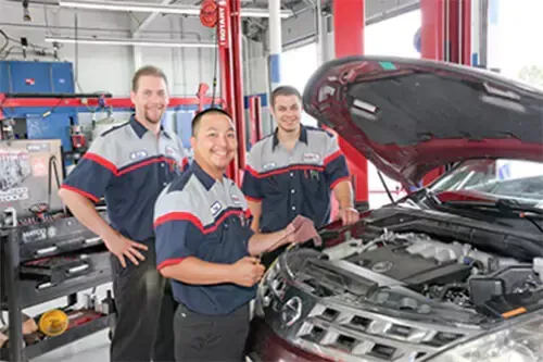 A group of mechanics are working on a car in a garage.